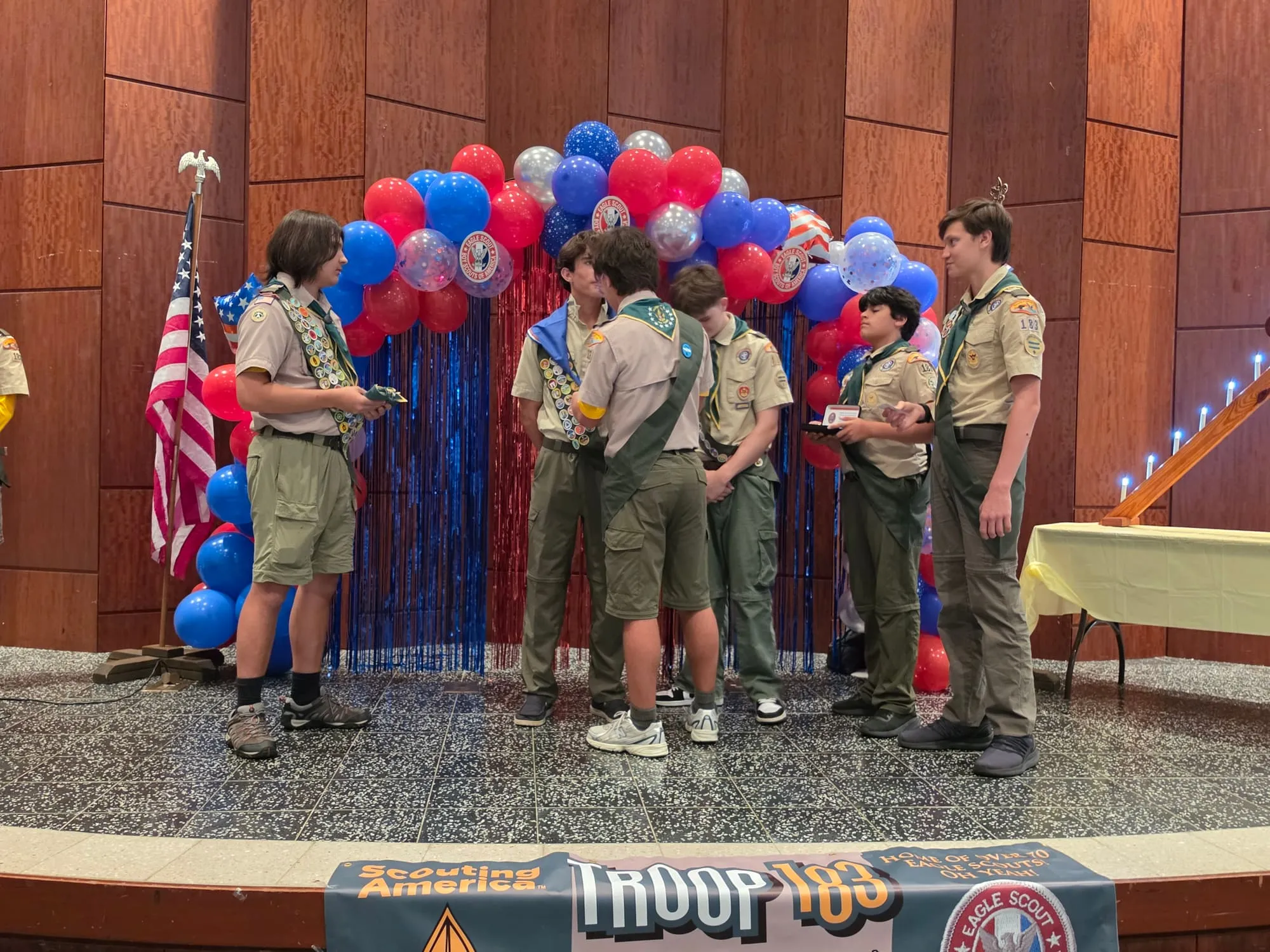 Scouts gather on stage under a balloon arch during a Troop 183 Court of Honor.